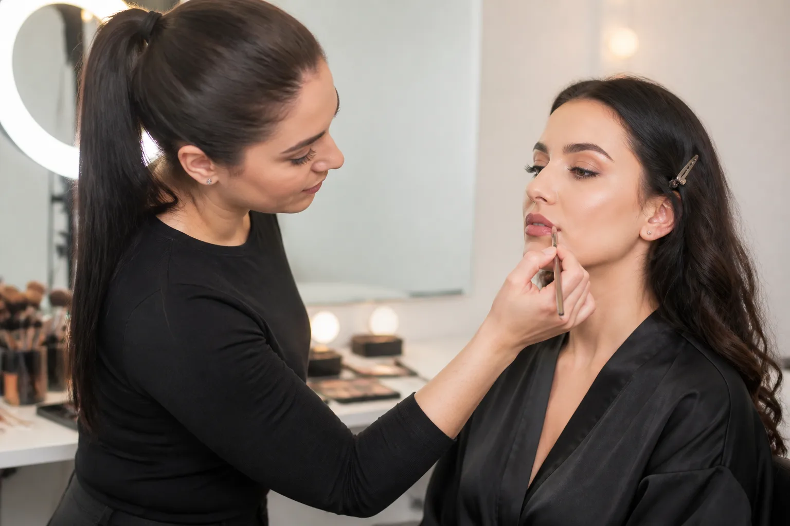 Makeup artist applying makeup to a client in a bright studio