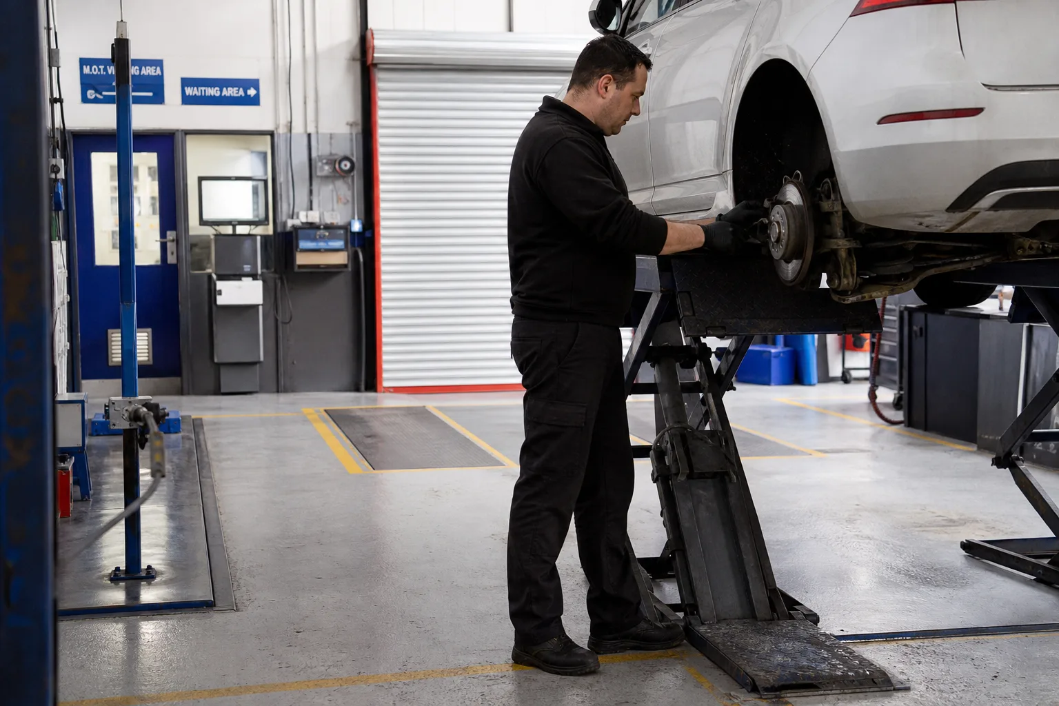 Technician inspecting a car during an MOT test